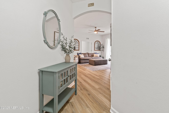hallway featuring arched walkways and light wood-style flooring