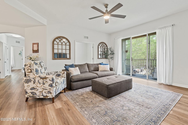 living area with arched walkways, ceiling fan, wood finished floors, and baseboards