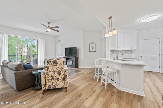 living room with light wood-style flooring, ceiling fan, and baseboards