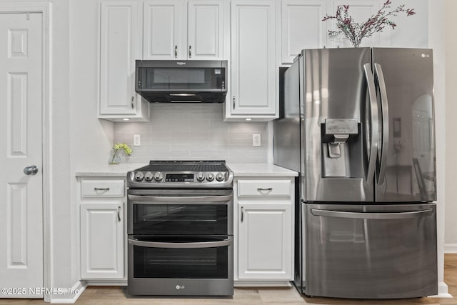 kitchen featuring stainless steel appliances, white cabinetry, backsplash, light wood-style floors, and light stone counters