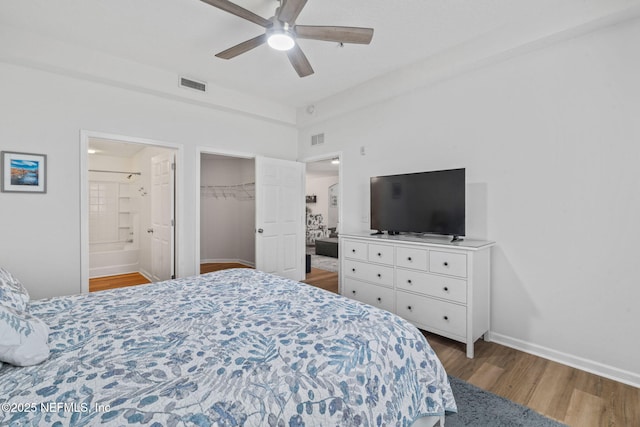 bedroom with wood finished floors, baseboards, connected bathroom, ceiling fan, and a closet