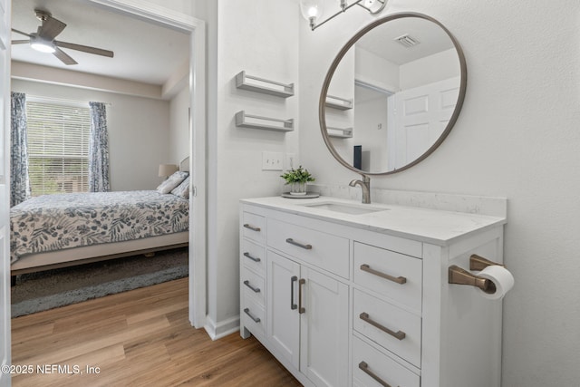 ensuite bathroom with wood finished floors, a ceiling fan, vanity, and baseboards