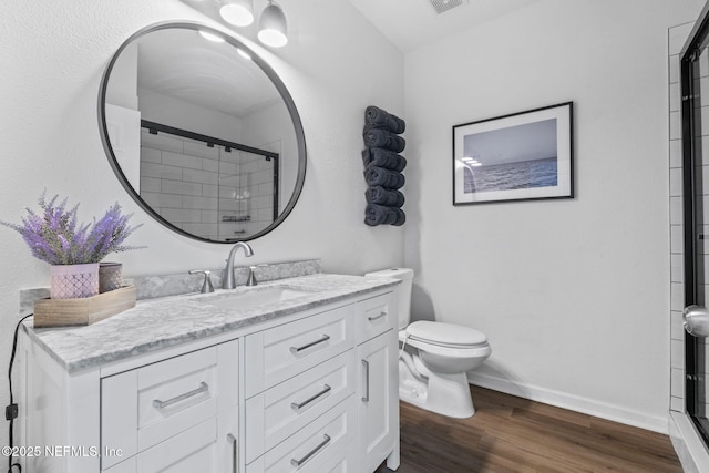 full bath featuring wood finished floors, toilet, a stall shower, baseboards, and vanity