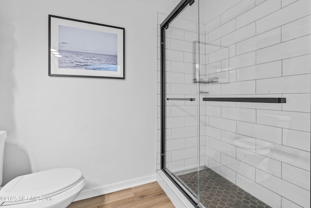 full bathroom featuring a shower stall, toilet, and wood finished floors