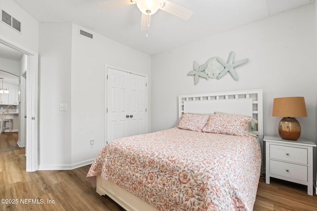 bedroom with wood finished floors, baseboards, a closet, and a ceiling fan