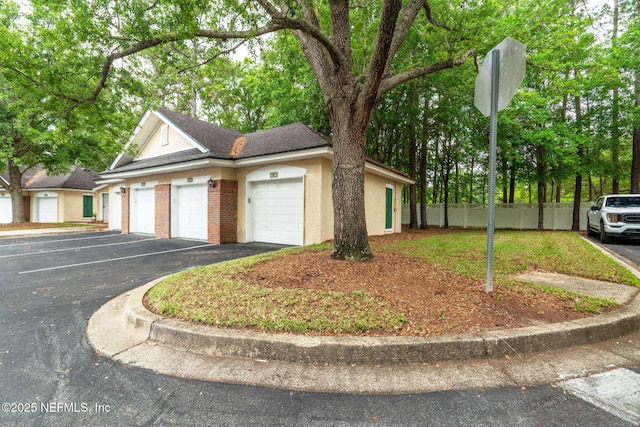 view of front of property with fence, driveway, stucco siding, and roof with shingles