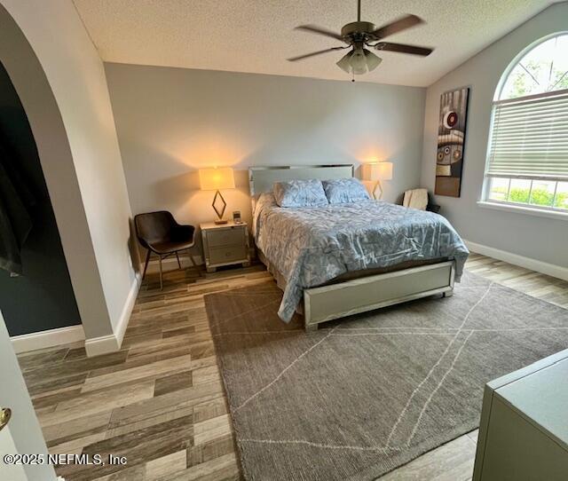 9536 Glenn Abbey Way, Jacksonville, FL 32256 - bedroom featuring arched walkways, a textured ceiling, multiple windows, lofted ceiling, and wood finished floors