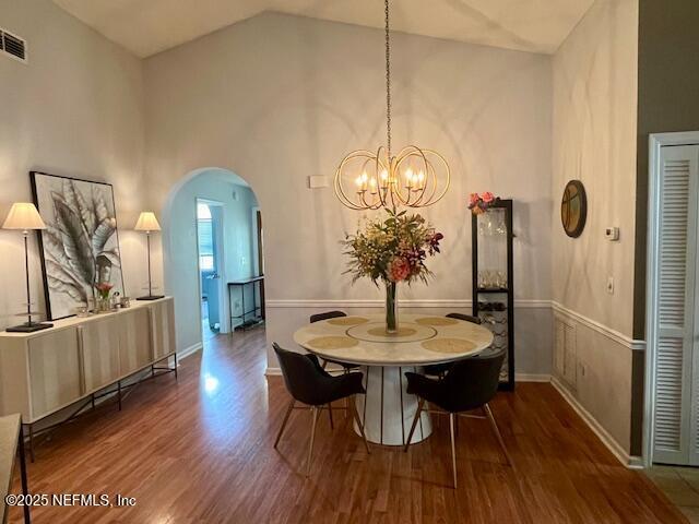 9536 Glenn Abbey Way, Jacksonville, FL 32256 - dining space with arched walkways, wood finished floors, a chandelier, baseboards, and high vaulted ceiling