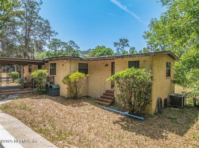 view of front of property featuring brick siding and central AC