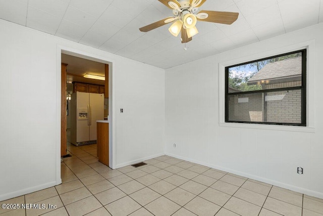 empty room with baseboards, ceiling fan, and light tile patterned floors