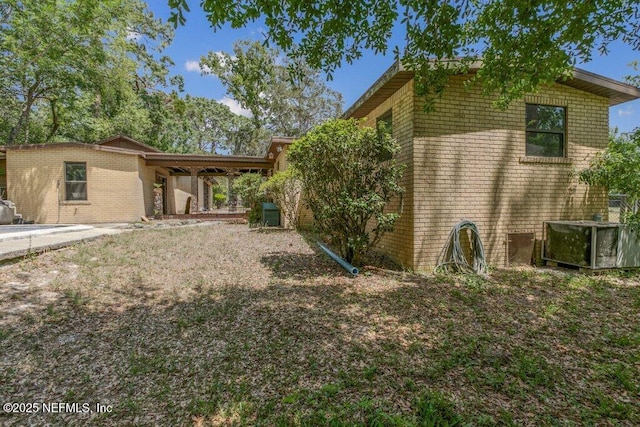 view of home's exterior featuring brick siding and central AC