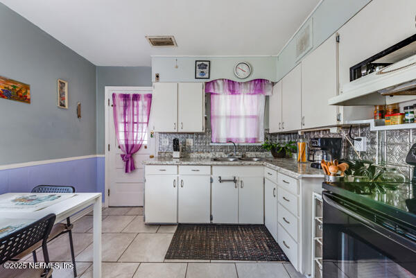 2760 Jerry Ln, Jacksonville, FL 32218 - kitchen with range with electric stovetop, a sink, white cabinetry, light countertops, and backsplash