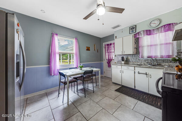 2760 Jerry Ln, Jacksonville, FL 32218 - kitchen with stainless steel fridge, a sink, ceiling fan, white cabinetry, and light countertops