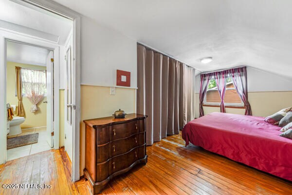 2760 Jerry Ln, Jacksonville, FL 32218 - bedroom featuring hardwood / wood-style flooring, multiple windows, vaulted ceiling, and connected bathroom