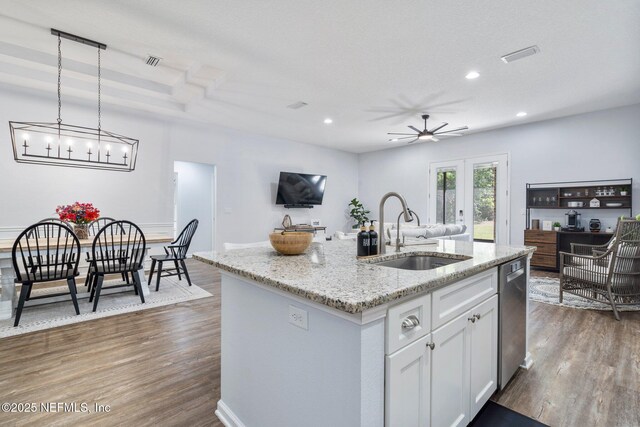 1309 Foxmeadow Trl, Middleburg, FL 32068 - kitchen with a sink, stainless steel dishwasher, dark wood-style flooring, an island with sink, and white cabinetry