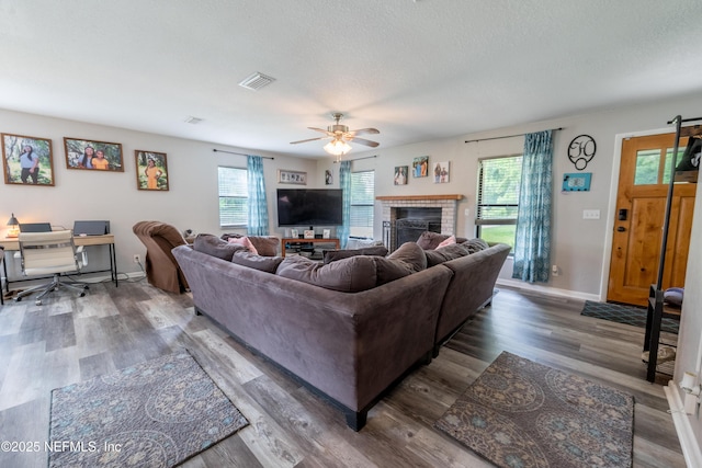 living room with wood finished floors, a ceiling fan, baseboards, a textured ceiling, and a fireplace