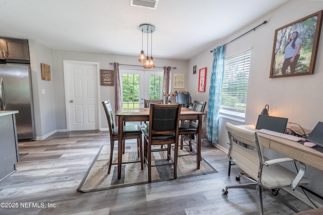 dining area featuring an office area, light wood finished floors, french doors, and baseboards