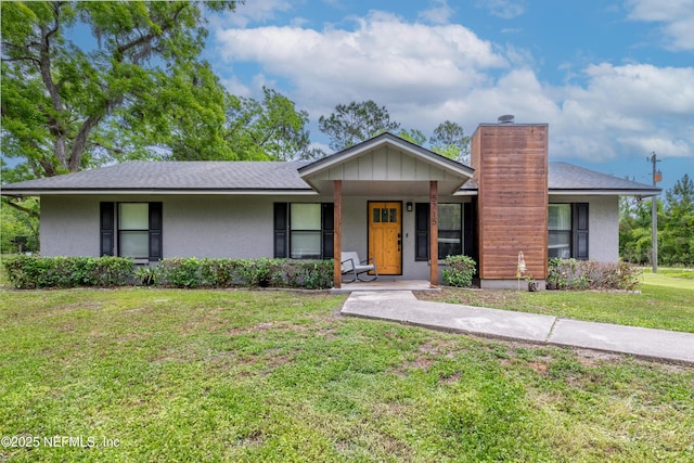 view of front of house featuring a chimney, a front lawn, stucco siding, a porch, and a shingled roof