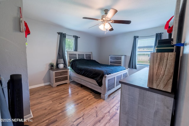 bedroom with light wood-style flooring, baseboards, and ceiling fan