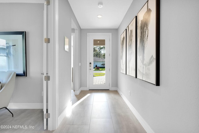 doorway with baseboards and light tile patterned floors