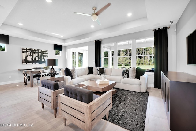 living room featuring recessed lighting, a ceiling fan, a raised ceiling, and baseboards
