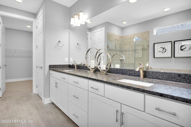 full bath with a stall shower, double vanity, a spacious closet, recessed lighting, and baseboards