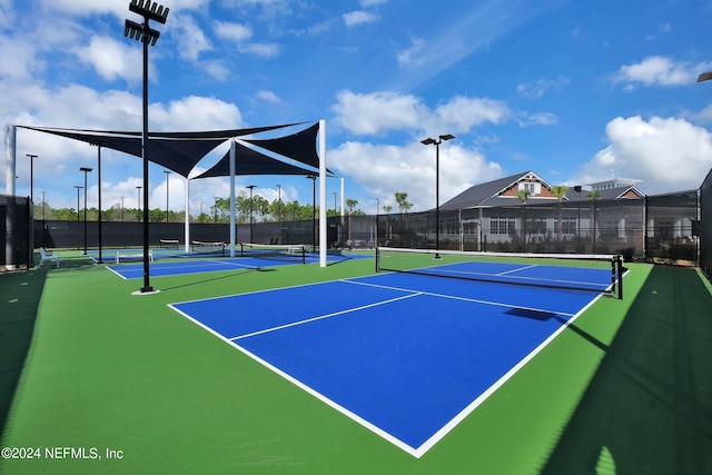 view of tennis court with community basketball court and fence