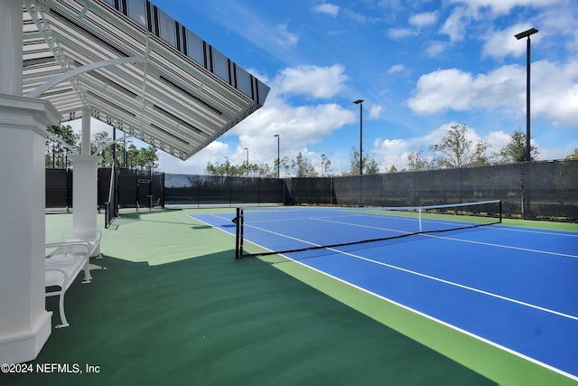 view of tennis court featuring community basketball court and fence