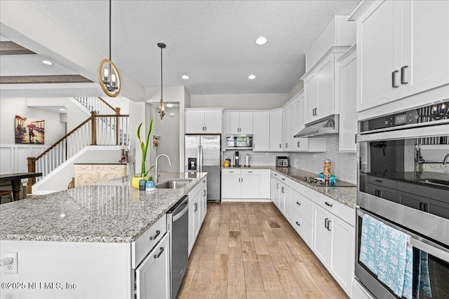 71 Lansing Ct, Saint Augustine, FL 32092 - kitchen with stainless steel appliances, a sink, light wood-type flooring, white cabinetry, and an island with sink