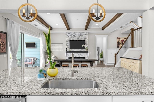 71 Lansing Ct, Saint Augustine, FL 32092 - kitchen featuring a chandelier, beamed ceiling, a sink, open floor plan, and light stone counters