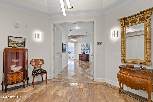 hall with marble tiled floors, baseboards, crown molding, and a tray ceiling