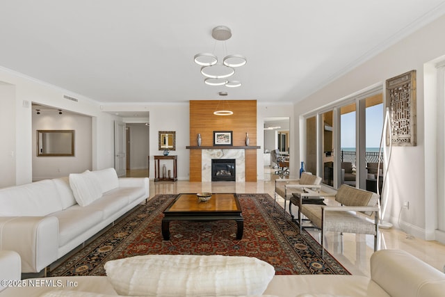 living room with ornamental molding, baseboards, a chandelier, and a premium fireplace