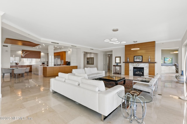living room featuring light marble finish flooring, ornamental molding, and a high end fireplace