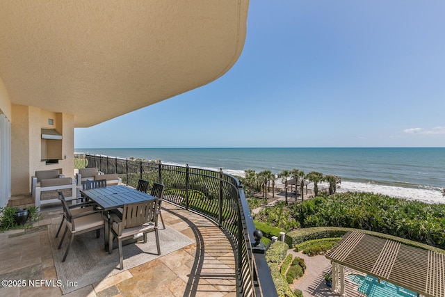 balcony featuring view of water and beach and outdoor dining space