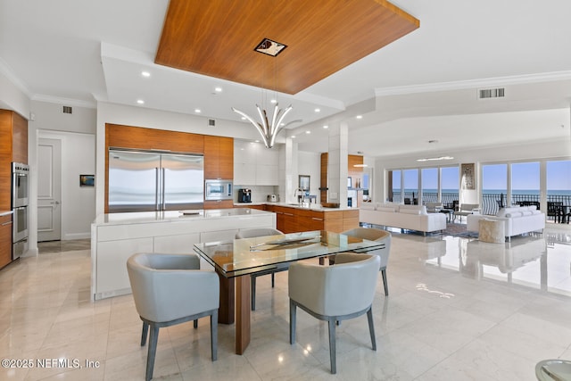 dining room with recessed lighting, crown molding, a water view, baseboards, and a chandelier