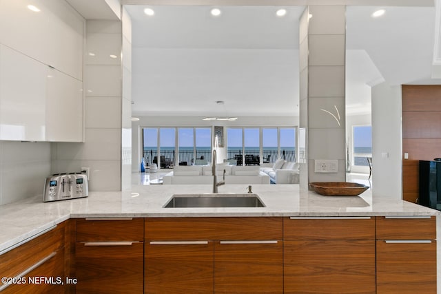 kitchen featuring modern cabinets, a sink, white cabinets, recessed lighting, and brown cabinets