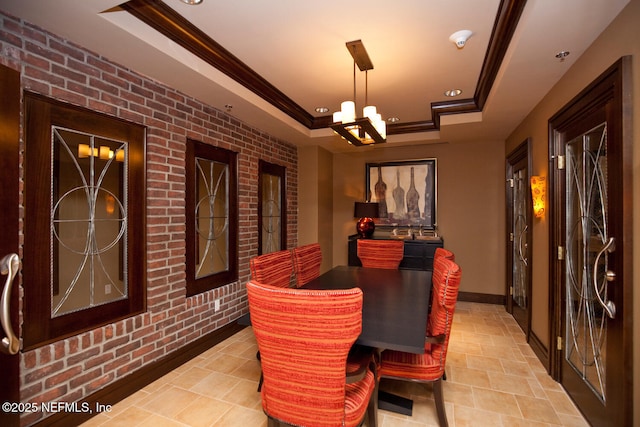 dining area with a tray ceiling, a chandelier, ornamental molding, recessed lighting, and brick wall
