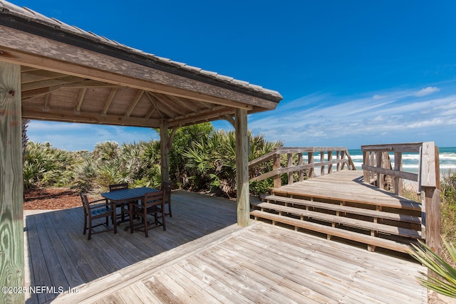 wooden deck with a water view, a gazebo, and outdoor dining area