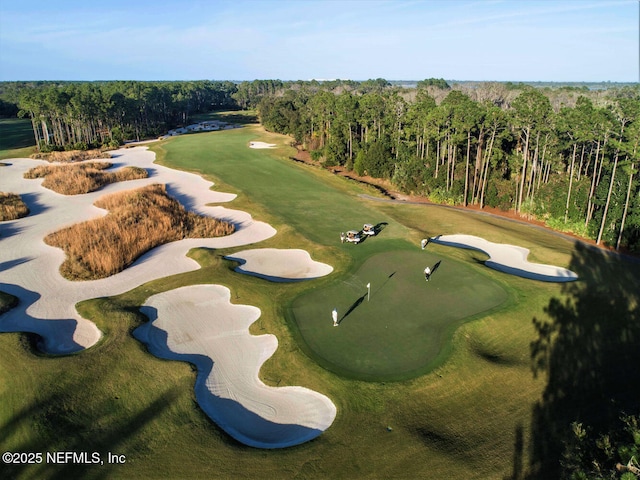 aerial view of property and surrounding area with a golf club and a heavily wooded area