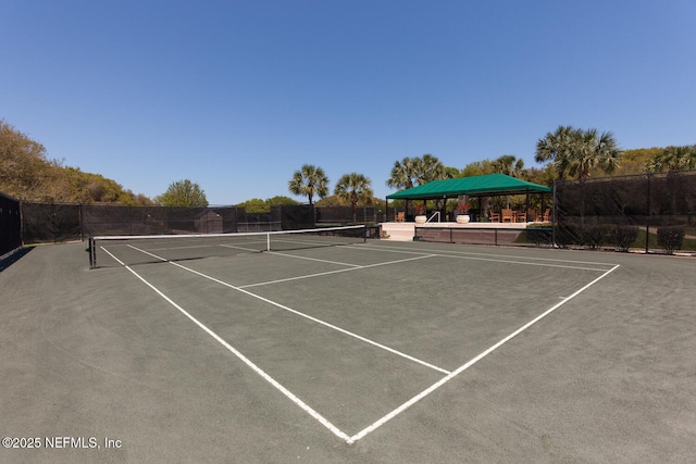 view of tennis court with fence, community basketball court, and a gazebo