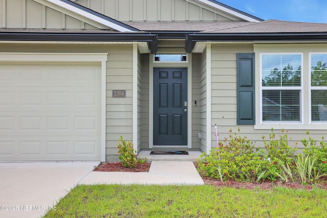 2304 Shady Breeze Ln, Green Cove Springs, FL 32043 - view of exterior entry featuring board and batten siding, concrete driveway, and a garage