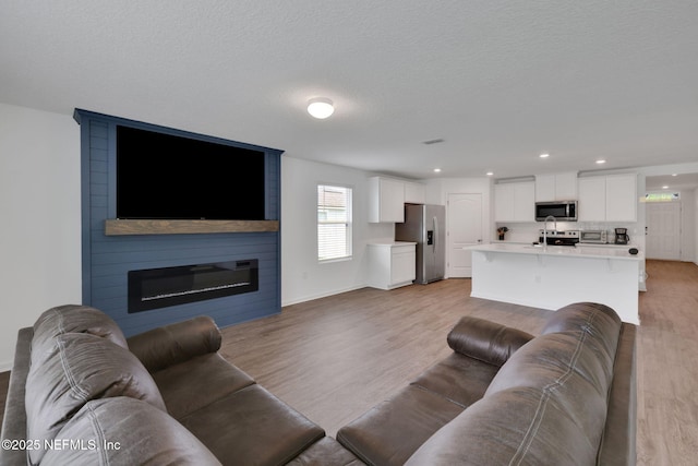 2304 Shady Breeze Ln, Green Cove Springs, FL 32043 - living area featuring light wood-style flooring, baseboards, a fireplace, recessed lighting, and a textured ceiling