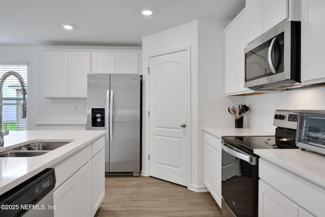 2304 Shady Breeze Ln, Green Cove Springs, FL 32043 - kitchen featuring stainless steel appliances, a sink, light wood-style flooring, white cabinetry, and recessed lighting