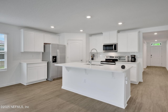 2304 Shady Breeze Ln, Green Cove Springs, FL 32043 - kitchen with stainless steel appliances, a sink, light wood finished floors, a center island with sink, and recessed lighting
