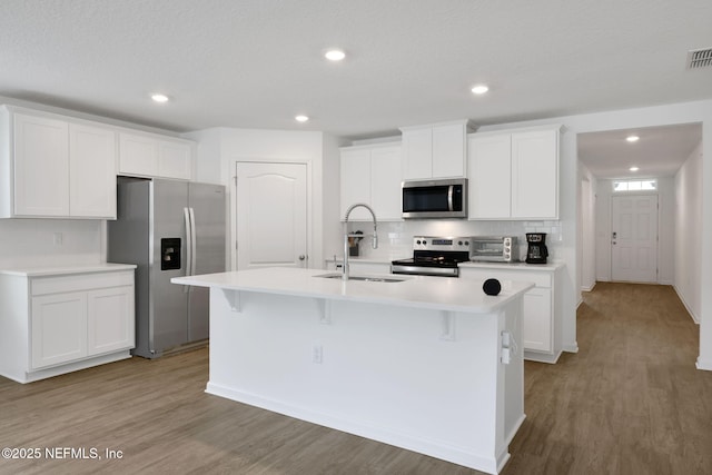 2304 Shady Breeze Ln, Green Cove Springs, FL 32043 - kitchen with appliances with stainless steel finishes, a sink, an island with sink, light countertops, and light wood-style flooring