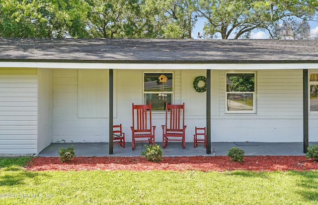 5388 Woodcrest Rd, Jacksonville, FL 32205 - doorway to property featuring covered porch, roof with shingles, and a lawn
