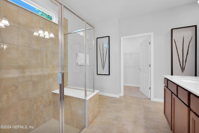 full bath featuring a shower stall, vanity, a spacious closet, and baseboards