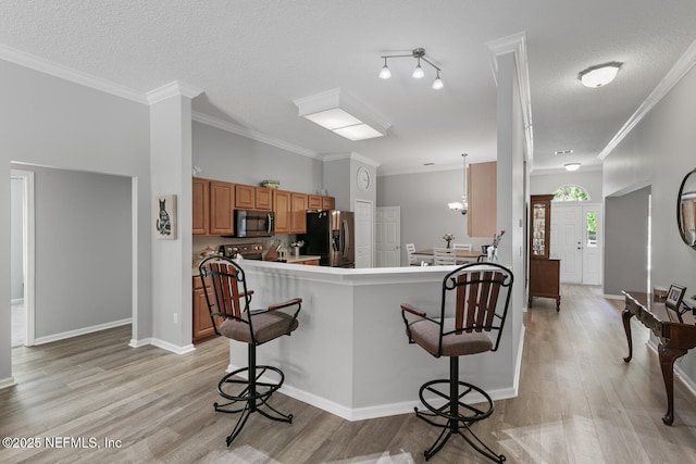 116 Greenfield Dr, Saint Johns, FL 32259 - kitchen featuring stainless steel appliances, a breakfast bar area, brown cabinetry, light wood-style flooring, and a textured ceiling