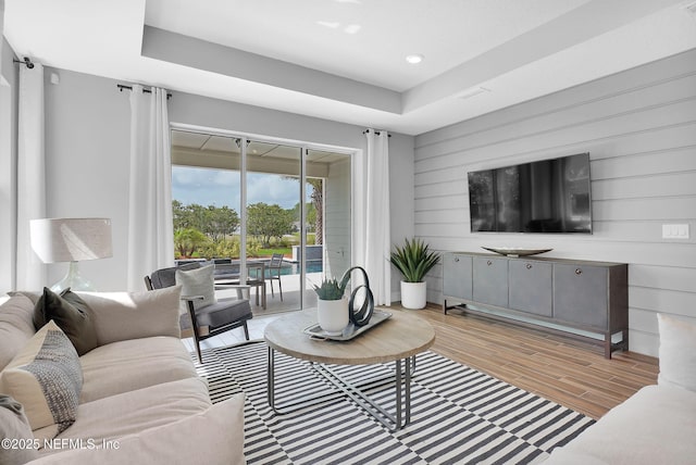 living room featuring light wood-style flooring, wood walls, and recessed lighting