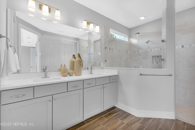 full bathroom featuring a walk in shower, double vanity, baseboards, and wood finish floors